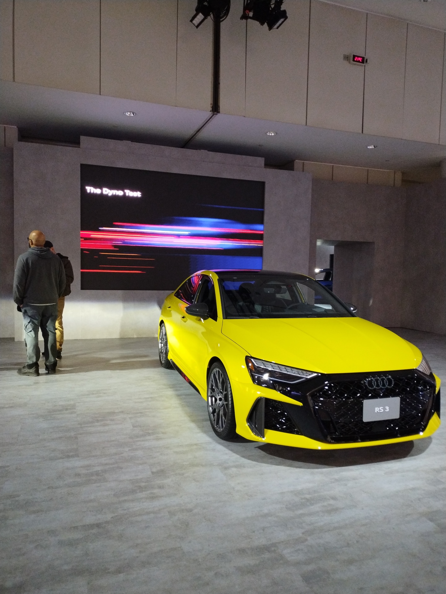 Yellow Audi RS 3 displayed in front of a large digital feature screen