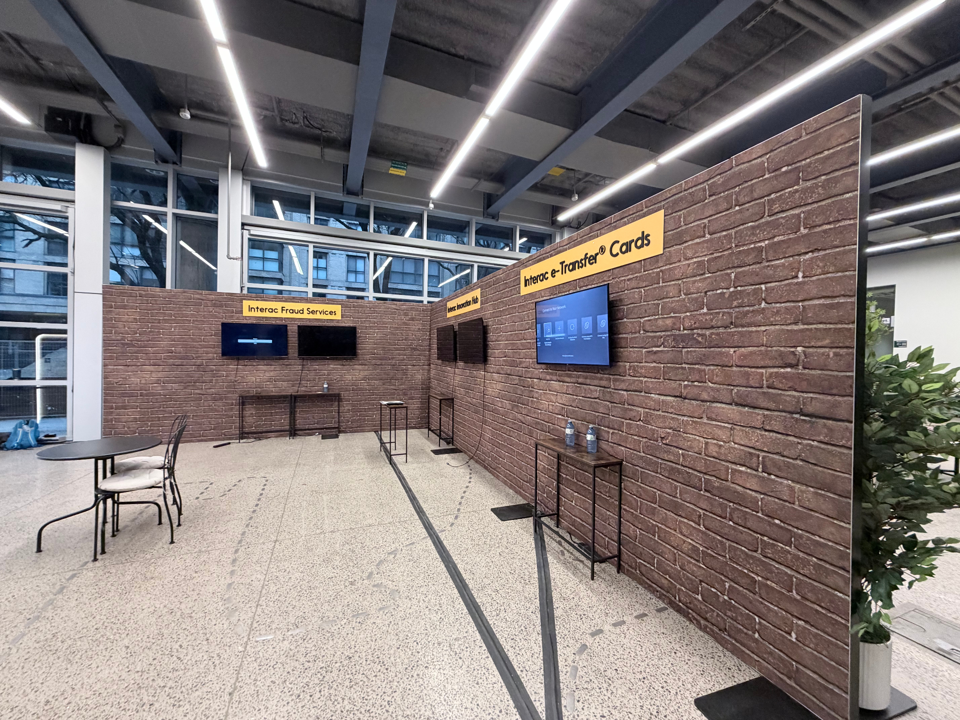 Interac brick-walled activation zone featuring Fraud Services, Innovation Hub, and e-Transfer Cards digital screens
