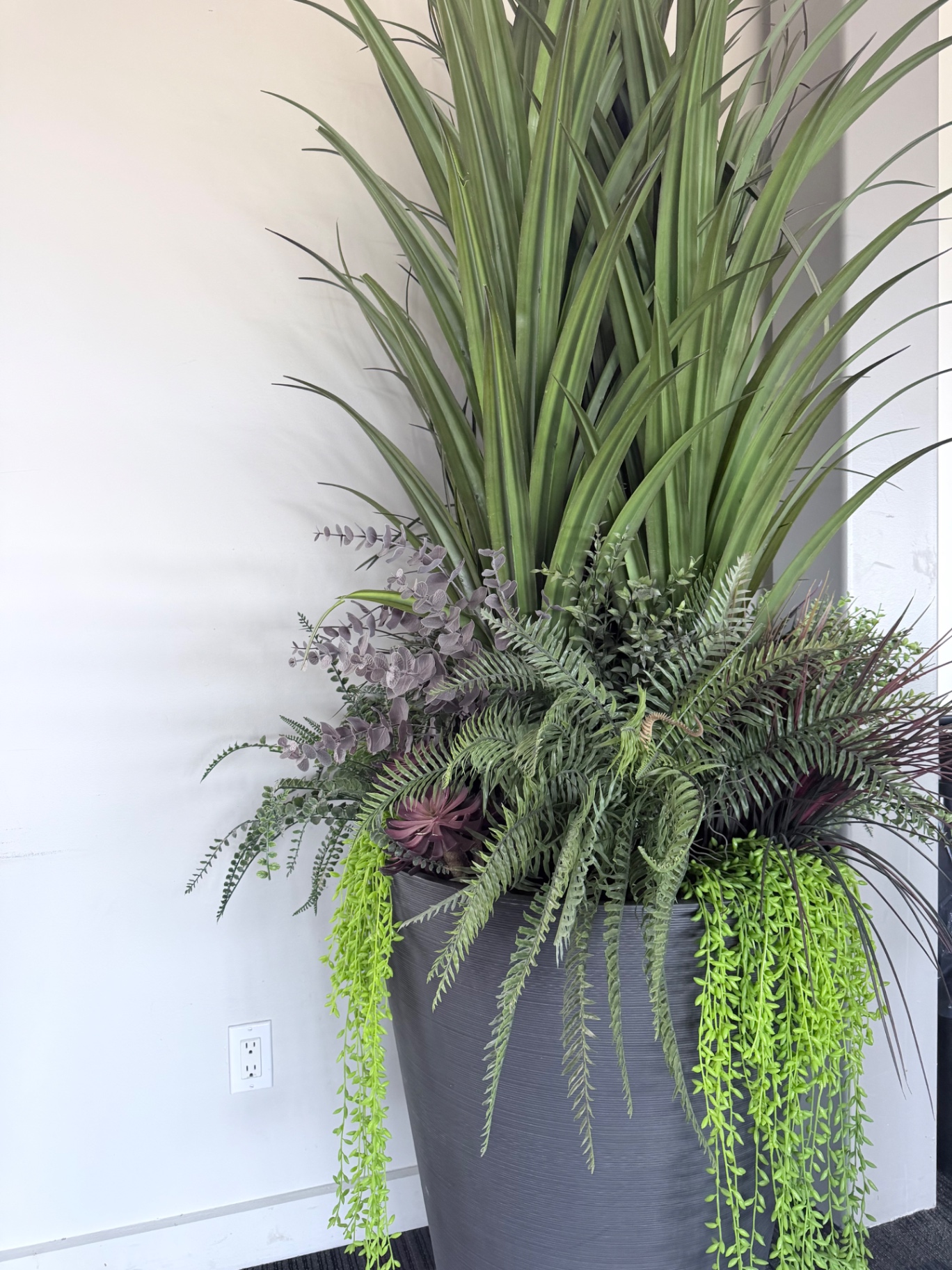 Spatial styling planter with grasses, ferns, and trailing greenery softening the Lamborghini hospitality environment