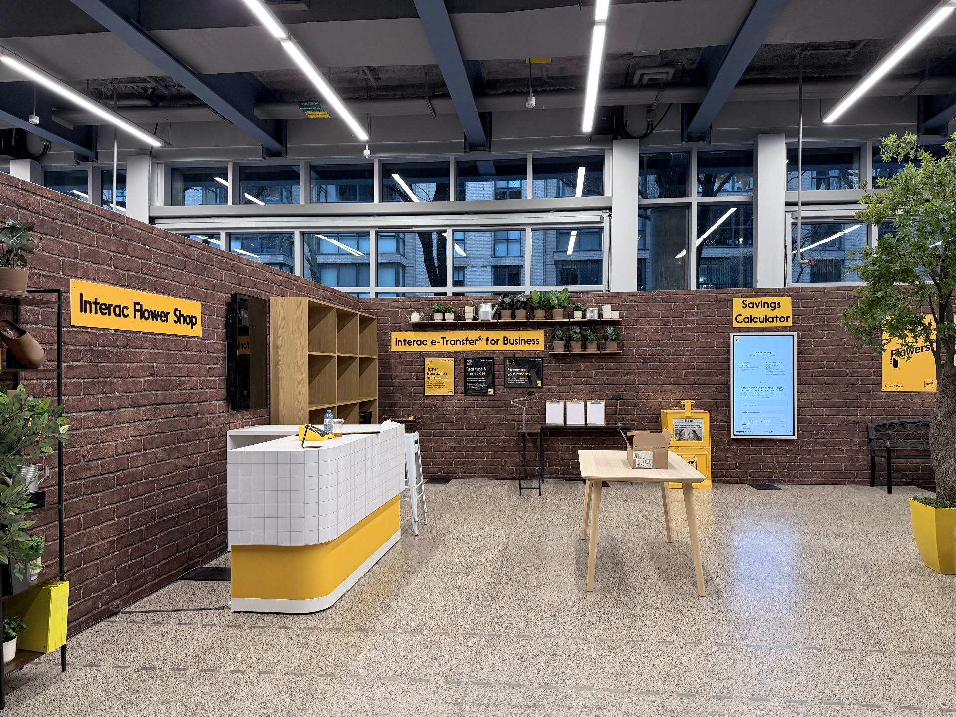 Interac merchant experience with flower shop counter, e-Transfer for Business wall, and digital savings calculator built with Mint Agency