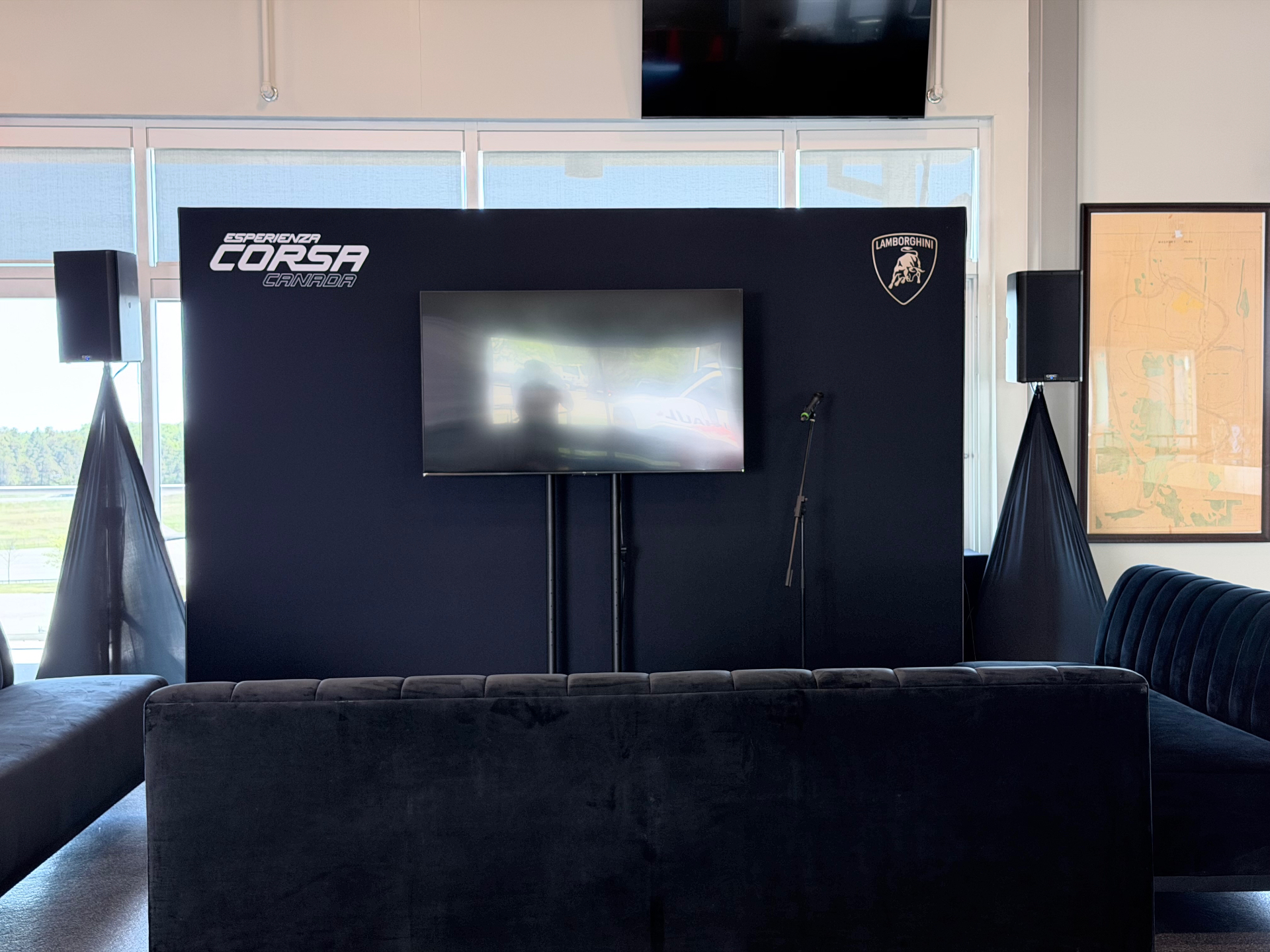 Esperienza Corsa Canada branded lounge wall with Lamborghini shield, mounted screen, and velvet seating inside the trackside clubhouse